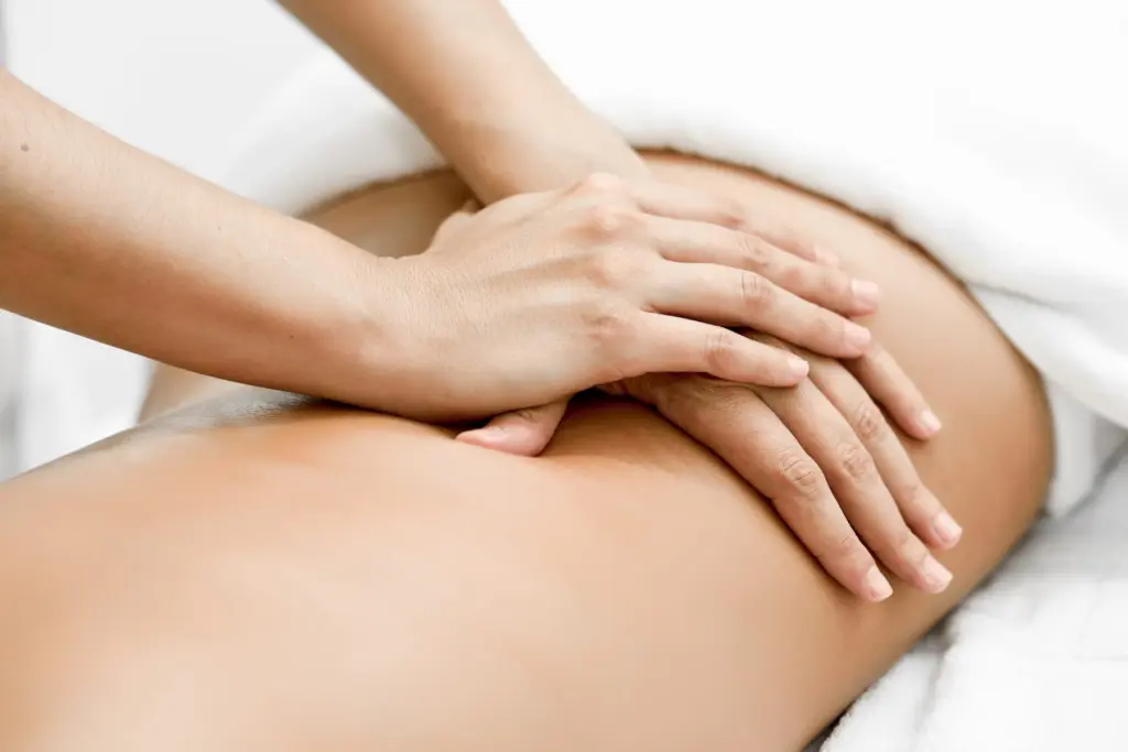 Two hands pressing gently on a patient's lower back