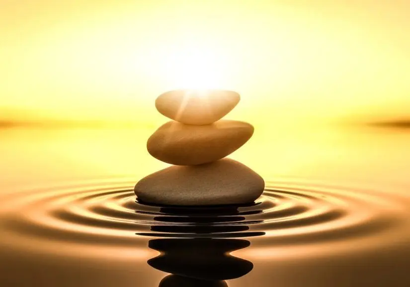 Smooth stones stacked in balance on still water at sunset